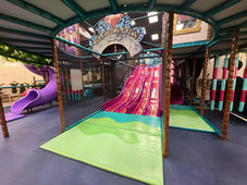 Vibrant playground play zone with climbing walls, tunnels, and slides.
